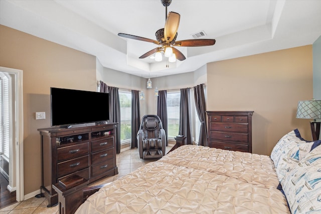 tiled bedroom featuring a tray ceiling and ceiling fan