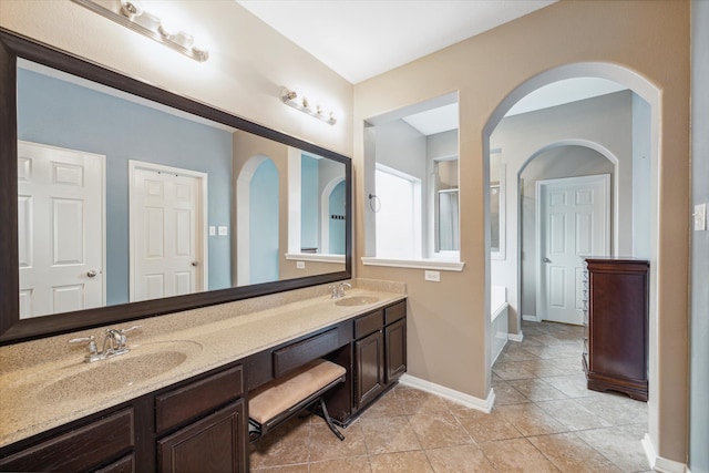 bathroom with tile patterned flooring, a bathtub, and vanity