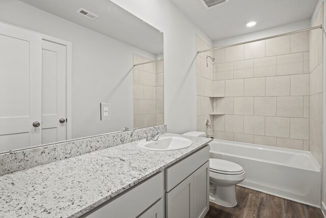 full bathroom featuring hardwood / wood-style flooring, toilet, vanity, and tiled shower / bath