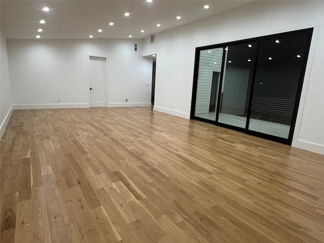 spare room featuring high vaulted ceiling and light hardwood / wood-style flooring