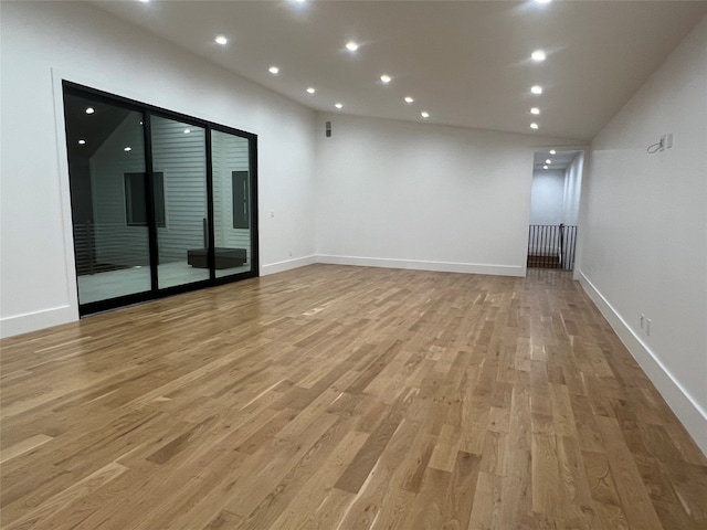 empty room featuring light wood-type flooring and vaulted ceiling