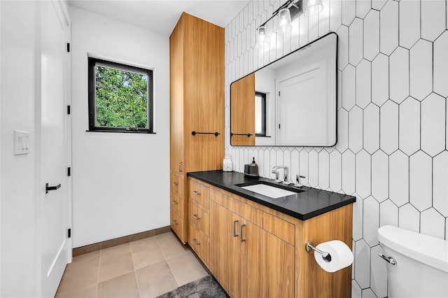 bathroom featuring vanity, tile patterned flooring, toilet, and tasteful backsplash