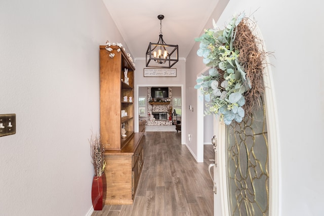 hallway with dark wood-type flooring, an inviting chandelier, and crown molding