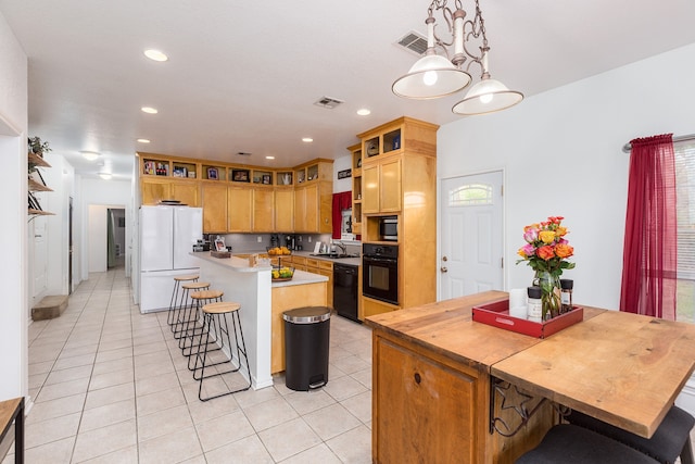 kitchen featuring black appliances, a breakfast bar area, sink, a kitchen island, and decorative light fixtures