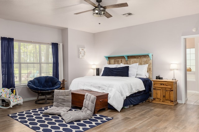 bedroom featuring light hardwood / wood-style floors, ceiling fan, and connected bathroom