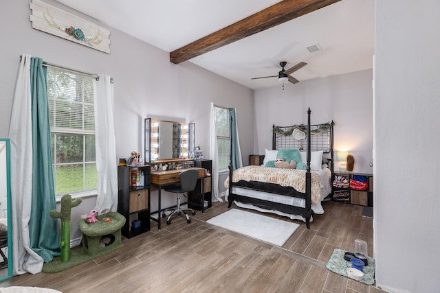 bedroom with hardwood / wood-style floors, beamed ceiling, ceiling fan, and multiple windows