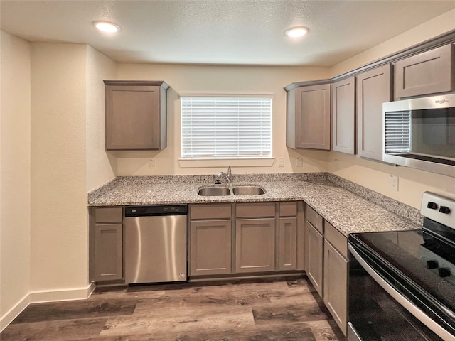 kitchen featuring light stone countertops, appliances with stainless steel finishes, sink, and dark hardwood / wood-style floors