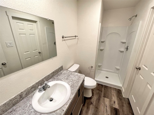 bathroom featuring a shower, hardwood / wood-style flooring, vanity, and toilet