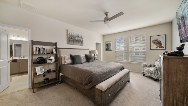 bedroom featuring ensuite bathroom, light carpet, and ceiling fan