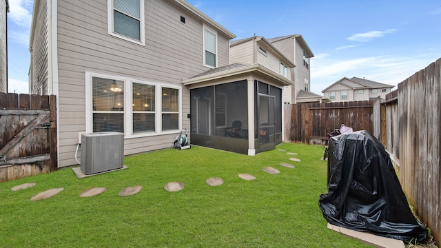 rear view of property with central AC unit, a lawn, and a sunroom