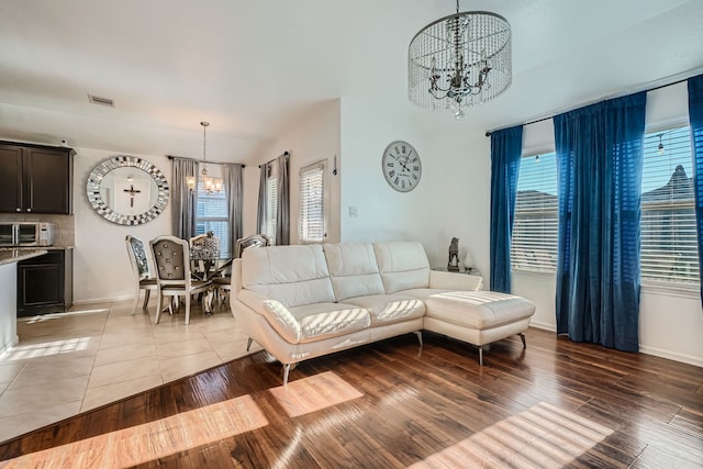 living room featuring plenty of natural light, light hardwood / wood-style flooring, and a notable chandelier