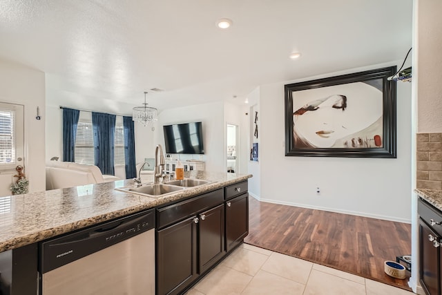 kitchen featuring dishwasher, sink, light stone countertops, light hardwood / wood-style flooring, and decorative light fixtures