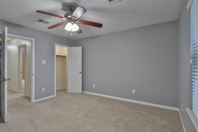 unfurnished bedroom featuring visible vents, light carpet, a ceiling fan, baseboards, and attic access