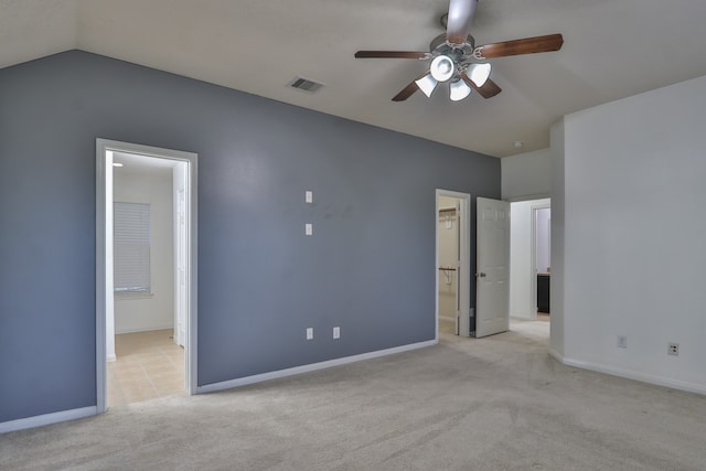 unfurnished bedroom featuring ceiling fan, a spacious closet, light colored carpet, connected bathroom, and vaulted ceiling