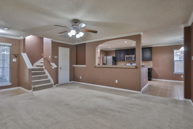 unfurnished living room featuring light colored carpet, ornamental molding, light tile patterned floors, a textured ceiling, and a ceiling fan