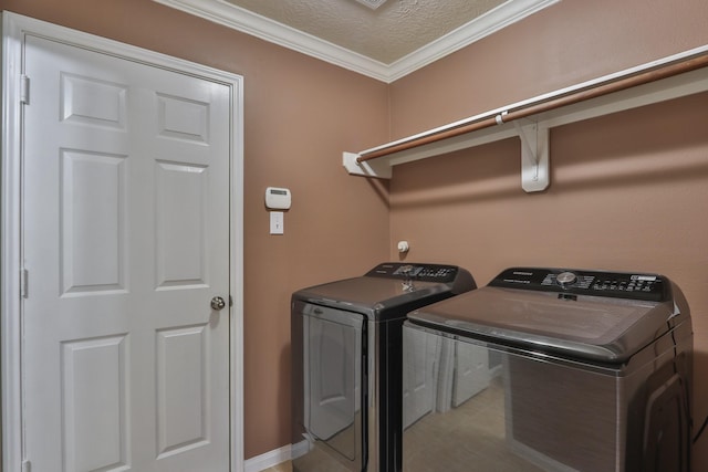 clothes washing area featuring a textured ceiling, washing machine and dryer, laundry area, and crown molding