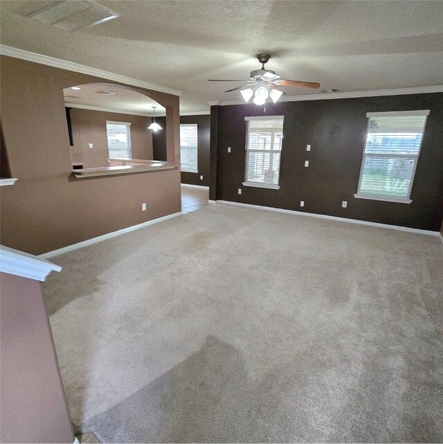 unfurnished living room with ceiling fan, carpet, baseboards, and ornamental molding