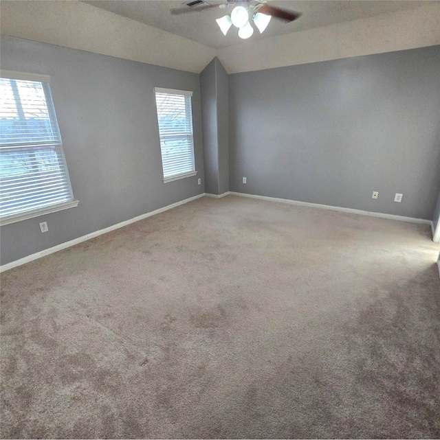 carpeted spare room featuring a wealth of natural light, baseboards, ceiling fan, and vaulted ceiling