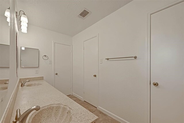 bathroom featuring tile patterned flooring, vanity, and a textured ceiling