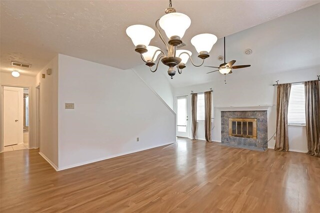 unfurnished living room featuring ceiling fan, wood-type flooring, a tiled fireplace, and vaulted ceiling