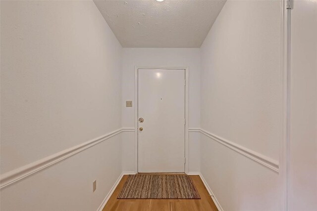 doorway with light wood-type flooring and a textured ceiling