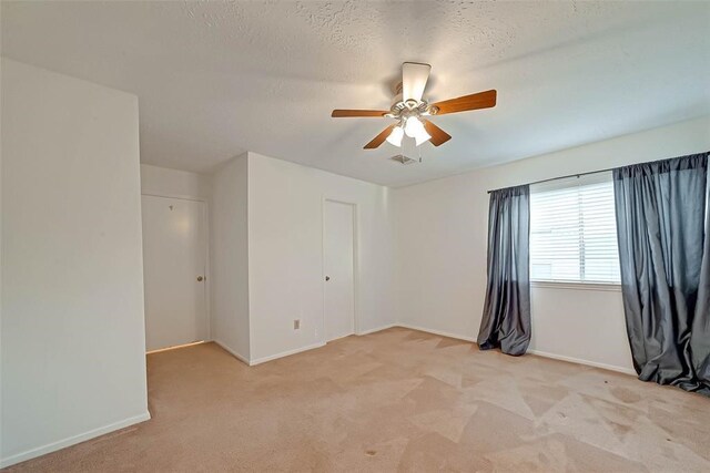 carpeted empty room with ceiling fan and a textured ceiling