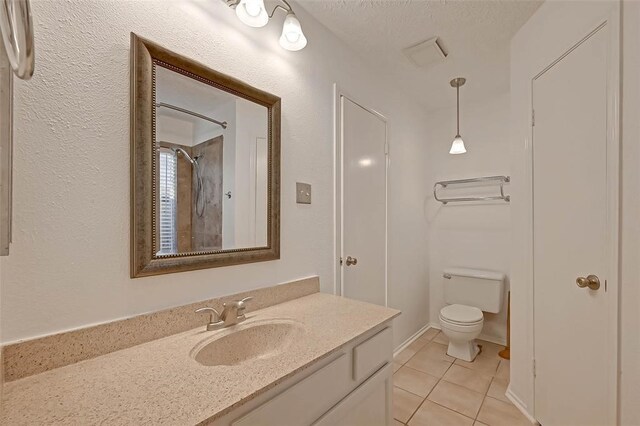 bathroom featuring toilet, tile patterned floors, a textured ceiling, vanity, and walk in shower