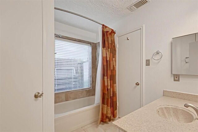 bathroom featuring vanity, shower / bath combination with curtain, a textured ceiling, and tile patterned flooring