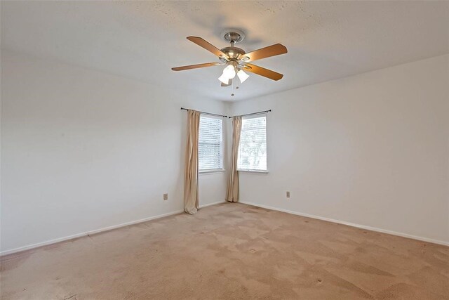 empty room with ceiling fan and light carpet