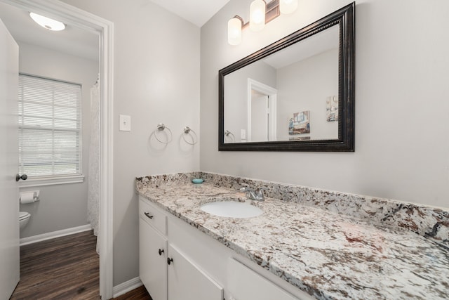 bathroom with toilet, vanity, and hardwood / wood-style flooring