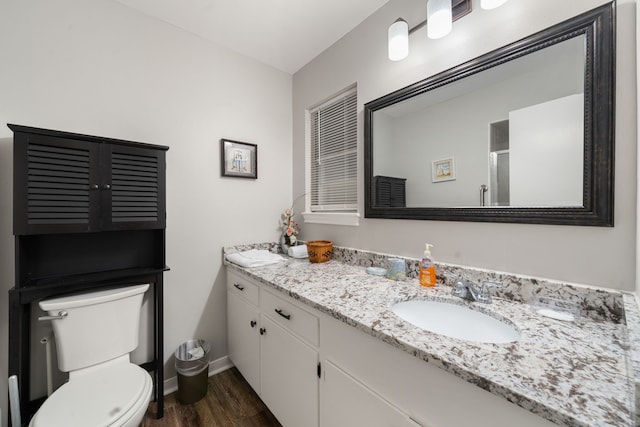 bathroom with hardwood / wood-style floors, vanity, toilet, and a shower with shower door