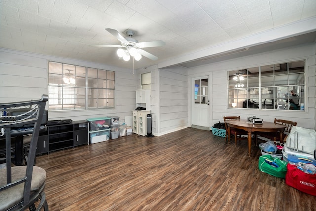 interior space with ceiling fan, dark hardwood / wood-style flooring, and wooden walls