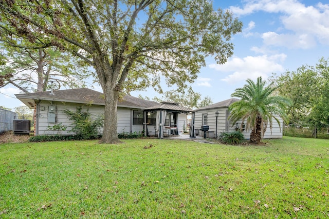 rear view of house featuring a gazebo, a yard, and central AC