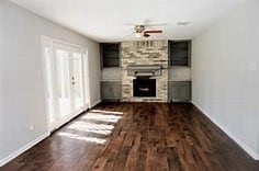 unfurnished living room with a fireplace, dark hardwood / wood-style flooring, and ceiling fan