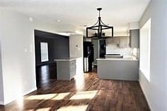 kitchen with black fridge, a notable chandelier, dark hardwood / wood-style floors, and gray cabinetry