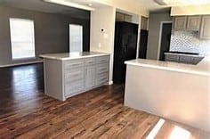 kitchen with kitchen peninsula, dark hardwood / wood-style flooring, and backsplash