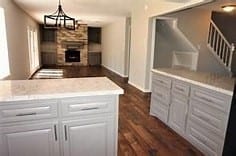 kitchen with a fireplace, white cabinetry, dark hardwood / wood-style floors, hanging light fixtures, and an inviting chandelier