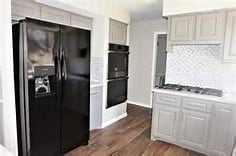 kitchen featuring black appliances, dark wood-type flooring, and backsplash