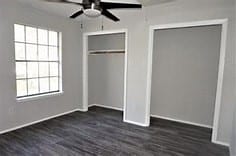 unfurnished bedroom with dark hardwood / wood-style floors, multiple windows, and a closet