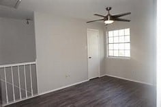 empty room with ceiling fan and dark hardwood / wood-style flooring