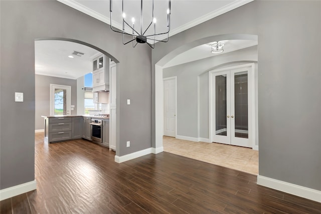 interior space with hardwood / wood-style flooring, a notable chandelier, french doors, and ornamental molding