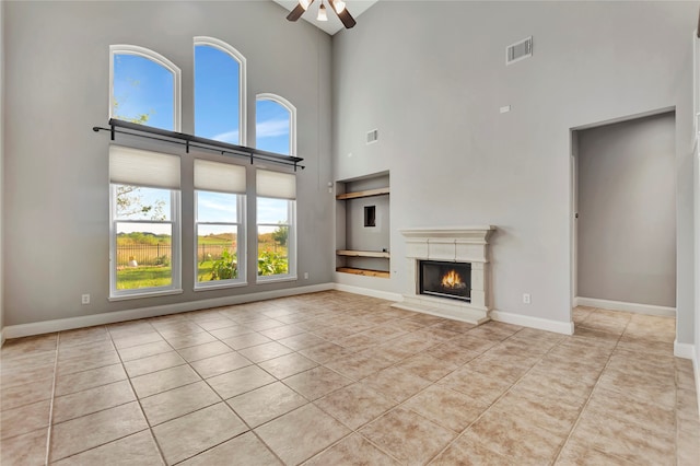 unfurnished living room featuring light tile patterned floors, a high ceiling, and ceiling fan