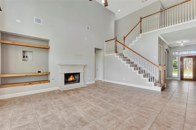 unfurnished living room featuring a high ceiling, light tile patterned floors, and ceiling fan