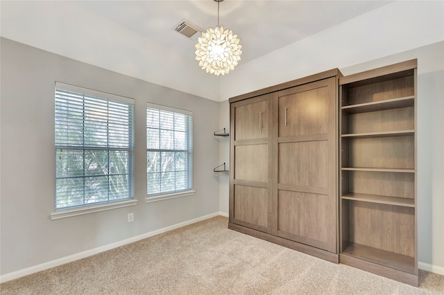 unfurnished bedroom with light carpet and a notable chandelier