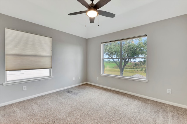 carpeted spare room featuring ceiling fan and plenty of natural light