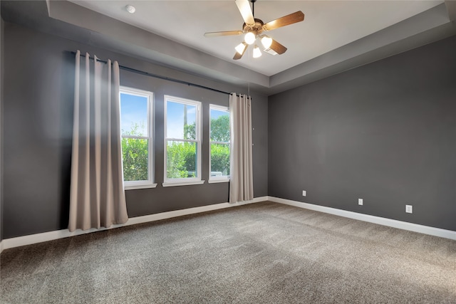 empty room featuring a tray ceiling, carpet, and ceiling fan