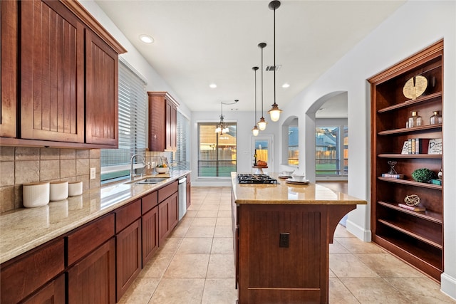 kitchen featuring decorative backsplash, a kitchen island, hanging light fixtures, and a healthy amount of sunlight