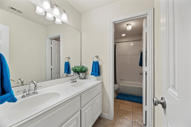 full bathroom featuring tile patterned floors, vanity, toilet, and tiled shower / bath combo