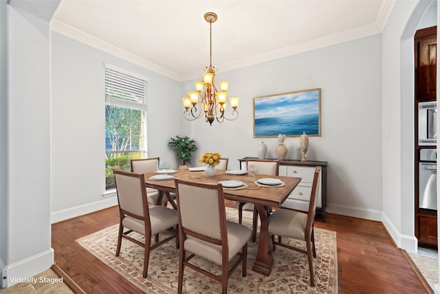 dining area with a chandelier, hardwood / wood-style floors, and crown molding