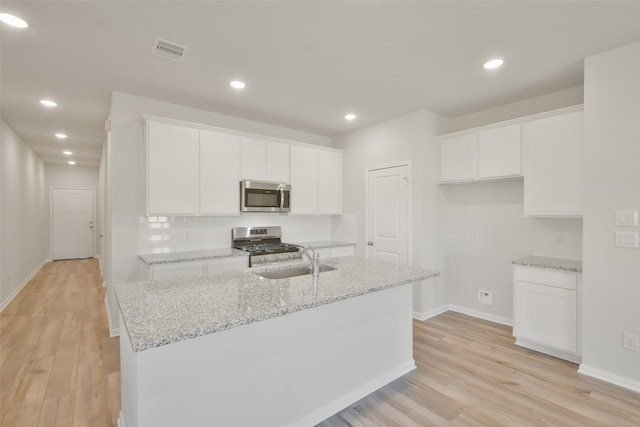 kitchen featuring light hardwood / wood-style floors, a center island with sink, sink, appliances with stainless steel finishes, and white cabinets